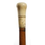 λ A Queen Anne ivory handled walking cane, dated '1700' and engraved with tulips and a bird and the