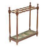 A late Victorian walnut stickstand, with twelve divisions and a green painted metal lift-out tray,