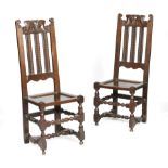 A pair of oak slat-back chairs, each with a scroll carved top rail, above triple leaf decorated