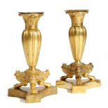A matched pair of Regency style gilt brass candlesticks, each with a detachable sconce, above a