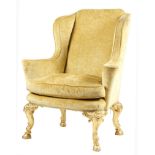 A giltwood wing armchair in the style of Giles Grendey, plush upholstered, with scroll arms, the