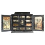 λ A 17th century Flemish Antwerp ebony table cabinet, the hinged top with a painted panel of figures