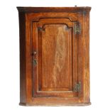 A mid-18th century oak hanging corner cupboard, with a fielded panel door, 89cm high, 66.8cm wide,