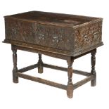 An early 17th century West Country oak box, the boarded hinged top above a carved front and sides,