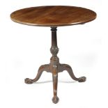 A George II mahogany tripod table, the circular tilt-top on a fluted urn turned stem, on leaf and