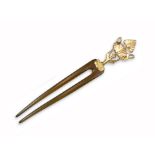 An early 20th century Egyptian revival hair pin, the horn two-prong pin is surmounted with a gold