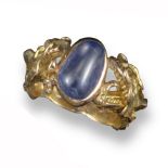 A sapphire-set dragon ring, the realistically formed dragons are clasping a cabochon sapphire