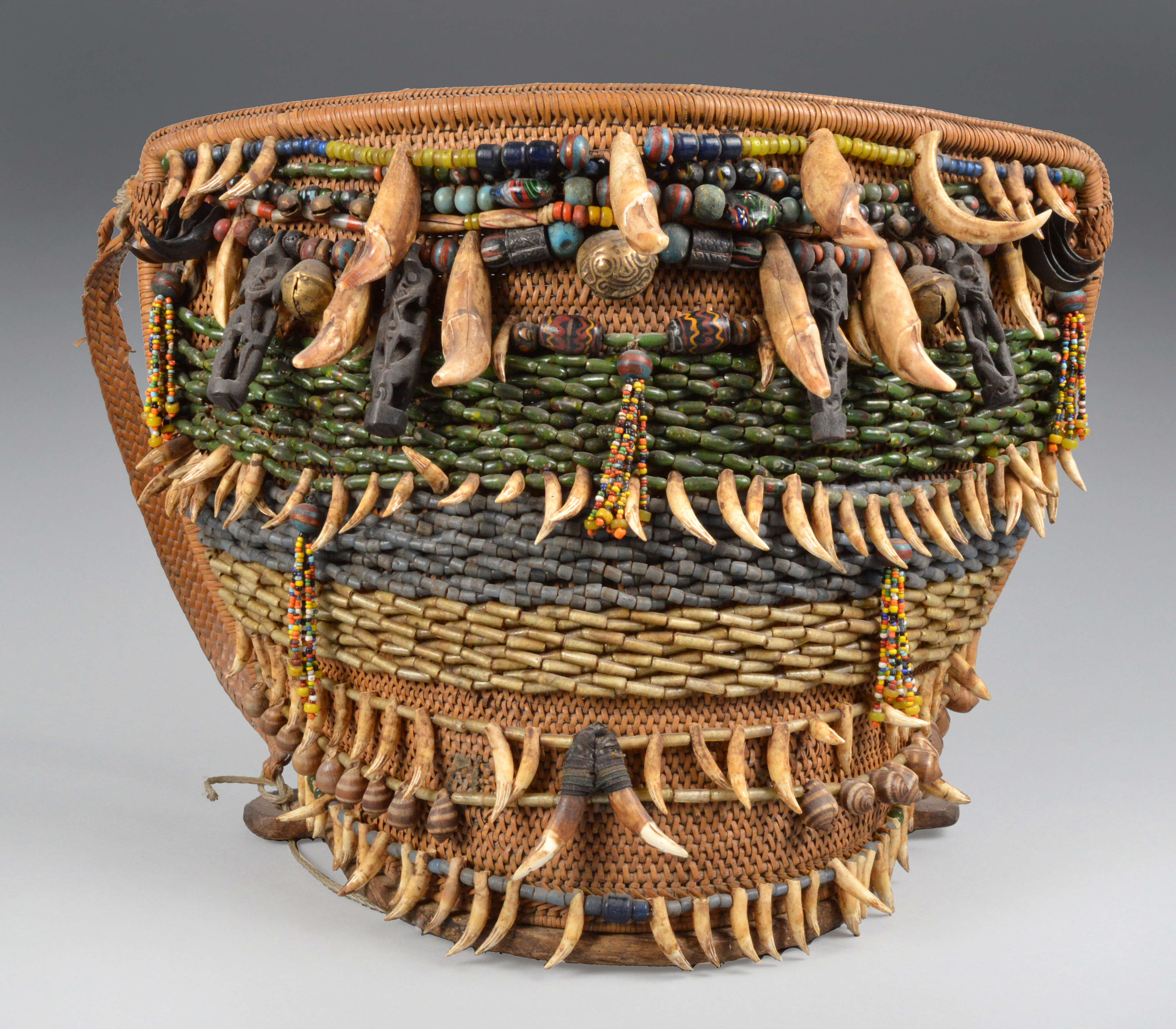 A Dayak baby carrier Borneo, Indonesia the basketry back hung with strings of glass beads, teeth,