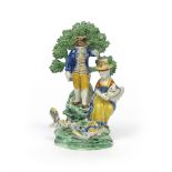 A rare Pratt ware figure group c.1800, modelled with a couple watching a cock fight, the two birds