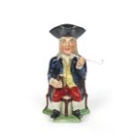 A Squire Toby jug c.1810-20, seated on a corner chair and holding a small jug of ale and a long-