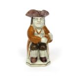 A pearlware Toby jug c.1800, of Ordinary type, wearing an ochre coat over a star patterned