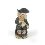 A Drunken Parson Toby jug c.1810, seated and pouring himself a cup of ale from a jug in his right