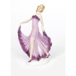 A porcelain model of a woman, model no. 8925, modelled wearing long, flowing purple dress, impressed