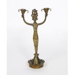An Austrian patinated bronze two-branch candlestick, modelled as a stylised exotic priestess,
