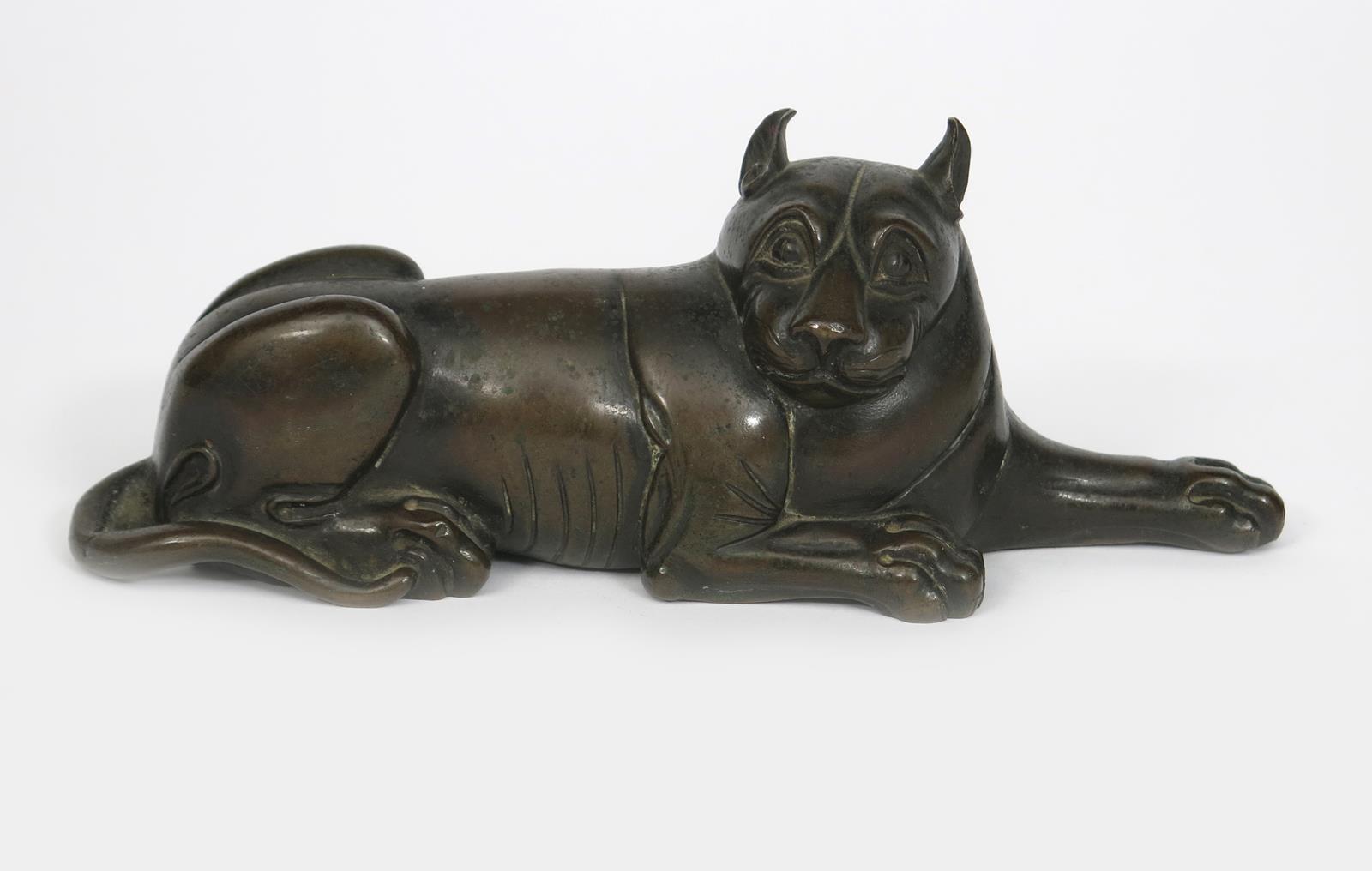 A patinated bronze model of a big cat, cast resting one front paw extended, head turned, stamped