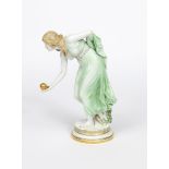 A Meissen porcelain model of a young lady bowling designed by Walter Schott, modelled in green