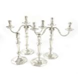 A modern cast silver suite of a pair of three-light candelabra and a pair of candlesticks, by Wakely