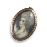 A George III portrait miniature pendant, depicting a woman in profile, within engine-turned gold