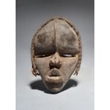 A Dan passport mask Ivory Coast with a vertical ridge to the forehead and a woven grass fibre
