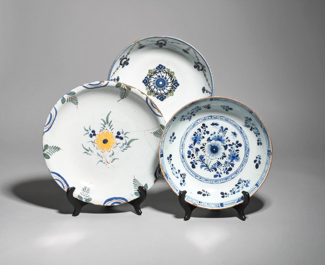 Three delftware shallow bowls c.1760-90, the largest painted in polychrome enamels with a central