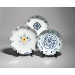 Three delftware shallow bowls c.1760-90, the largest painted in polychrome enamels with a central