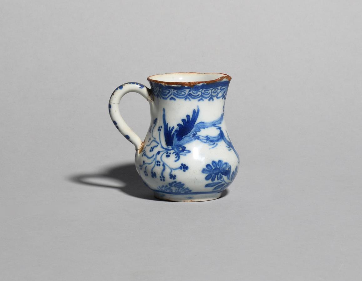 A delftware cream jug c.1760, the pear-shaped form painted in blue with a bird before flowering