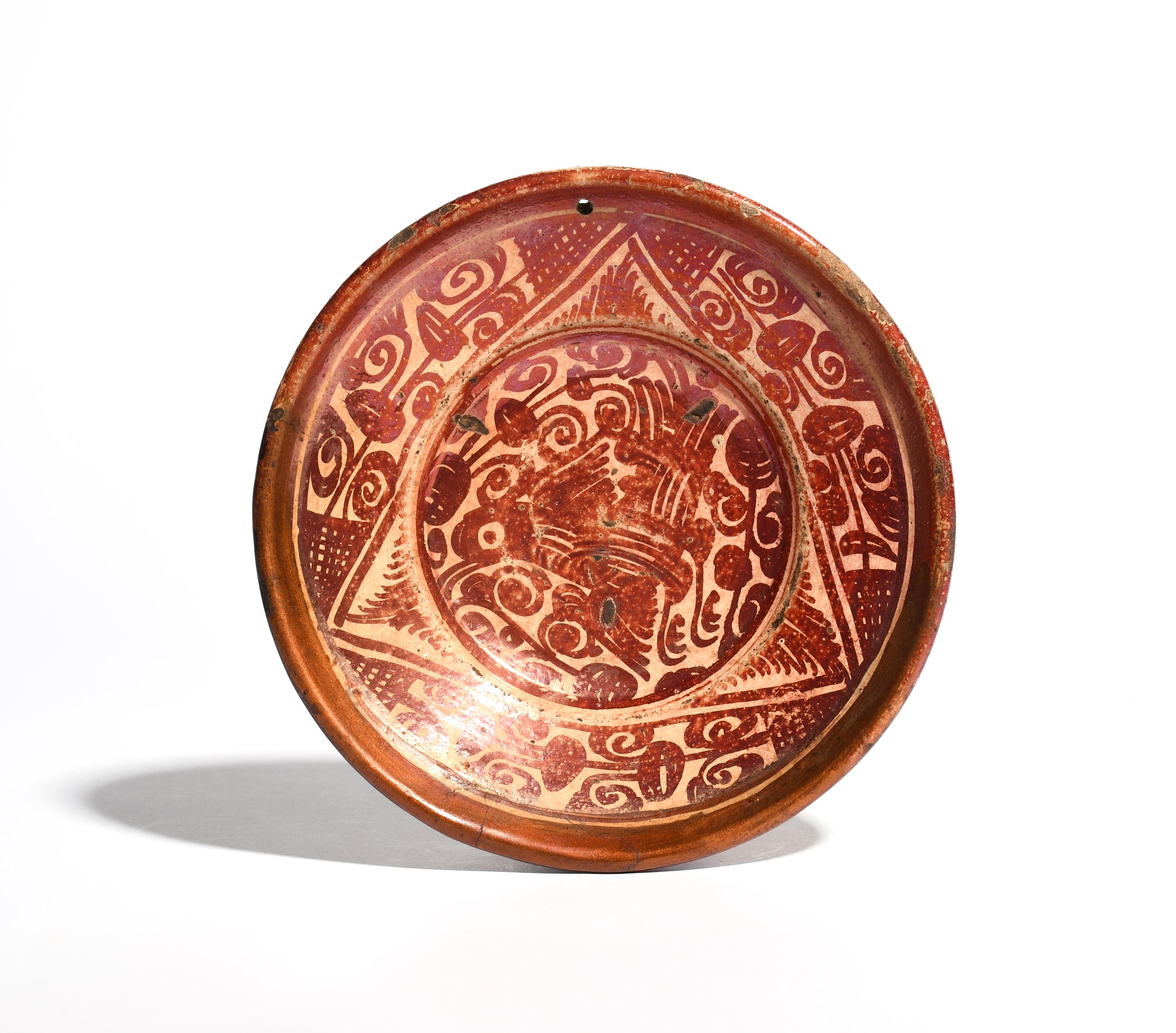 A small Hispano-Moresque dish 18th century, painted in deep copper lustre with a bird amid dense