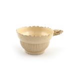 A rare creamware wine taster, c.1770, the circular ogee bowl moulded to the exterior with narrow