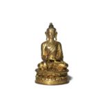 A TIBETAN GILT-BRONZE FIGURE OF BUDDHA SHAKYAMUNI 14TH CENTURY Seated in dhyanasana upon a beaded