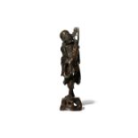 A CHINESE BRONZE FIGURE OF AN ASCETIC LUOHAN QING DYNASTY OR LATER Cast standing upon rockwork,