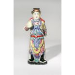 A CHINESE FAMILLE ROSE STANDING FIGURE 20TH CENTURY Depicted holding a large fruit in his right