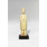 A CHINESE POTTERY STANDING FIGURE OF AN ATTENDANT TANG DYNASTY Depicted standing with his hands