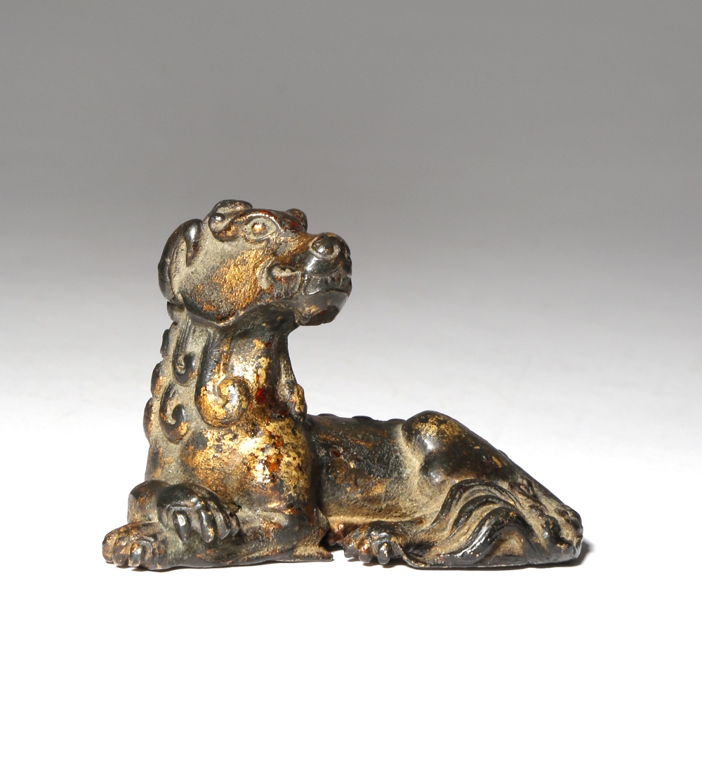 A CHINESE GILT-LACQUERED BRONZE MODEL OF A RECUMBENT CANID MING/QING DYNASTY Sitting with its head