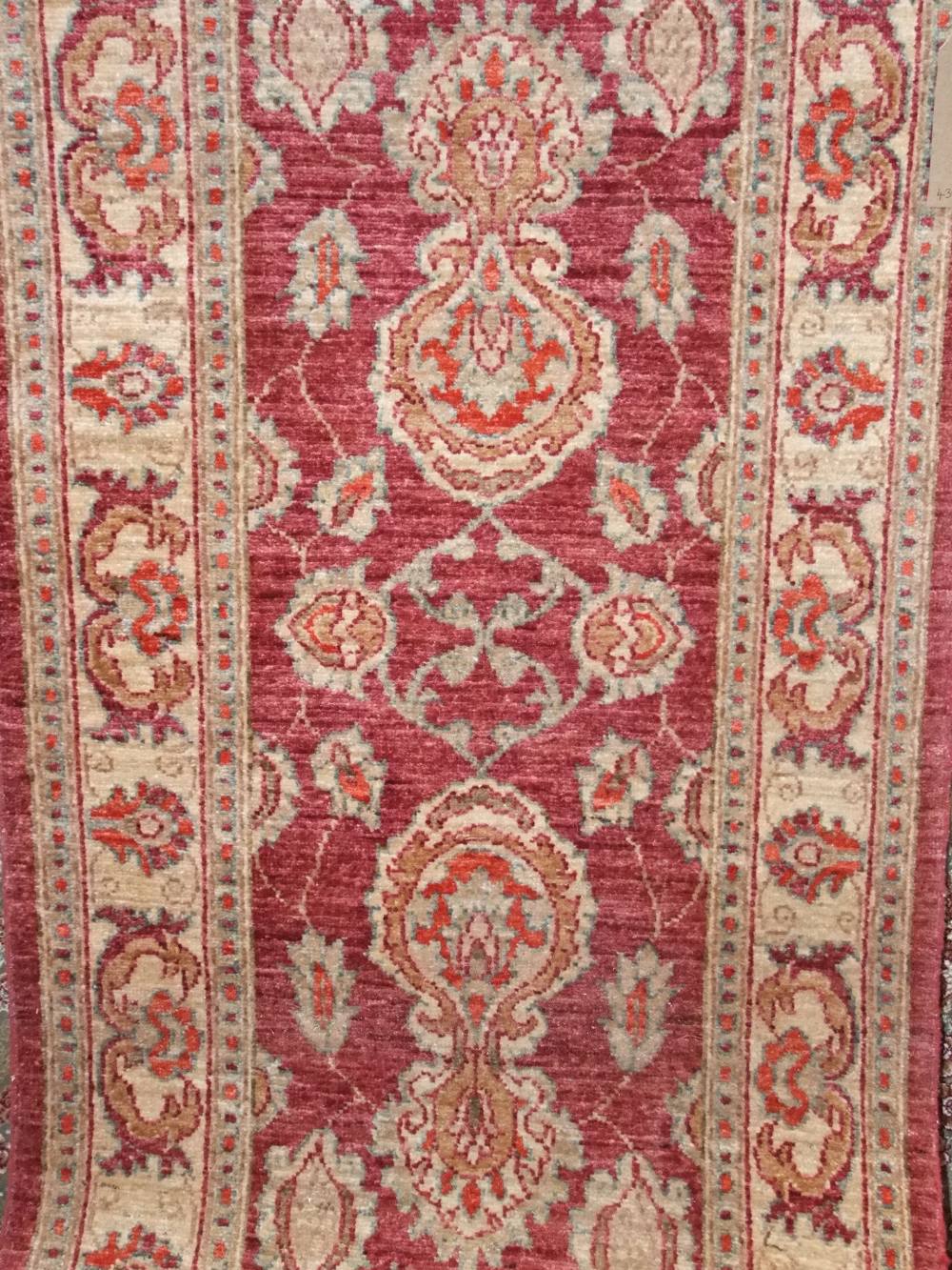 Persian long runner, decorated with geometric floral medallions upon a crimson ground, 430cm x 80cm