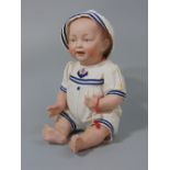 A bisque head character baby doll, with painted eyes - unmarked and dressed in a sailors outfit,