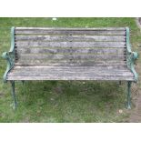 A three seat garden bench with weathered timber lathes, raised on a pair of green painted cast