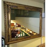 A carved and gilded period frame with repeating floral and geometric detail enclosing a later mirror
