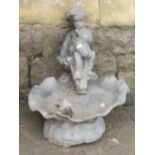 A small lead bird bath in the form of a seated cross legged cherub raised on a shell with bird and