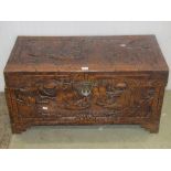 A carved camphor wood chest with character, landscape and sailing vessel detail, containing a number