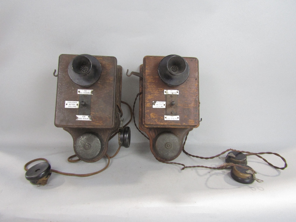 A pair of early wall mounted telephone receivers, oak cased with enamelled panels detailing the