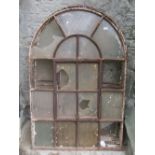 Three reclaimed cast iron framed windows of arched form with segmented glass panels and central