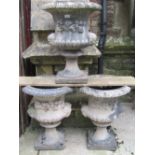 Three matching weathered cast composition stone campana shaped garden urns with flared egg and