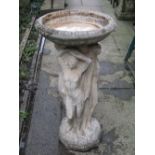 A contemporary cast composition stone birdbath with shallow circular bowl raised on a pedestal