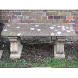 A weathered contemporary cast composition stone three sectional garden bench with rectangular slab
