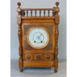 An Arts & Crafts oak cased mantle clock, painted enamelled dial and twin train movement, the case