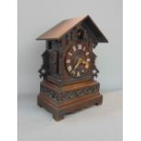 A Black Forest oak twin train cuckoo mantle clock fitted with Roman numerals in a typical carved