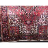 Traditional Persian carpet decorated with an elaborate central medallion upon a red ground, 300 x