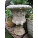 A cast composition stone campana shaped garden urn with flared egg and dart rim, face mask and