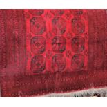 Good quality Bokhara carpet decorated with typical black geometric medallions upon a deep red