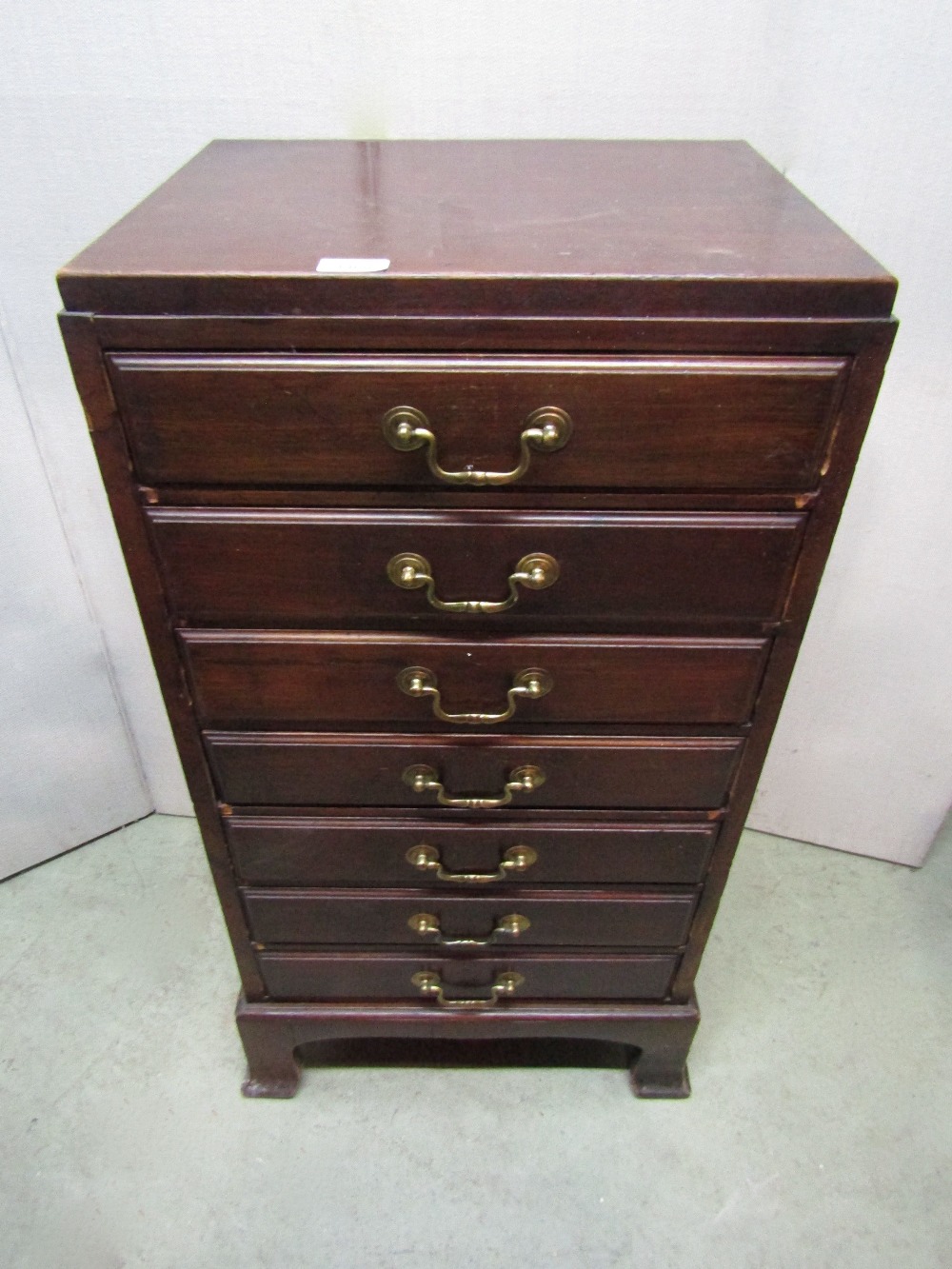 An Edwardian walnut sheet music cabinet fitted with a tower of seven drawers with fall fronts and